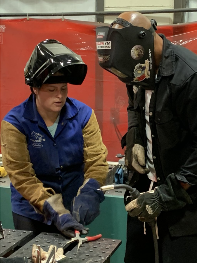 Instructor showing welding techniques to a student.