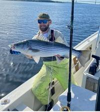 Malcolm Bowen in the bay holding a striped bass